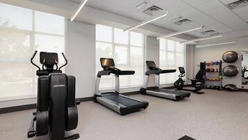 A gym with treadmills, elliptical machines, and exercise balls.