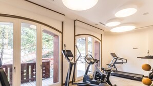 A home gym with exercise equipment, a treadmill, and a view through glass doors to an outdoor deck. - Spacious apartment at the foot of the slopes with SPA access (Méribel)