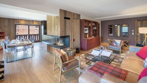 A spacious living area with a fireplace, a dining area, and a seating area with a sofa and chairs. - Spacious apartment at the foot of the slopes with SPA access (Méribel)