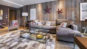 A modern living room with a wooden wall, a sofa, a coffee table, and a star decoration. - Spacious apartment at the foot of the slopes with SPA access (Méribel)