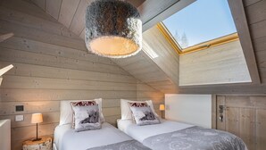 A cozy bedroom with two beds, a wooden ceiling, a skylight, and a small bedside table with a lamp. - Bright apartment for 6 in Méribel with fireplace (Méribel)