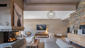 A modern living room with a fireplace, a stone wall, and a large painting of a skier. - Bright apartment for 6 in Méribel with fireplace (Méribel)