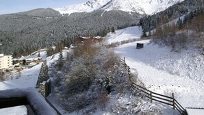 A snow-covered mountain landscape with a wooden fence and buildings in the foreground.