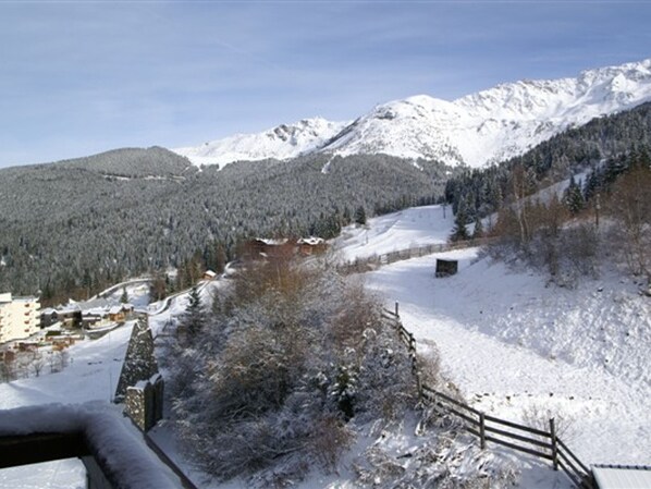 A snow-covered mountain landscape with a wooden fence and buildings in the foreground.
