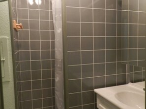 A bathroom with a white sink, a shower with a curtain, and tiled walls. - Studio 18m² for 3, near slopes, pets allowed (Le Pleynet)