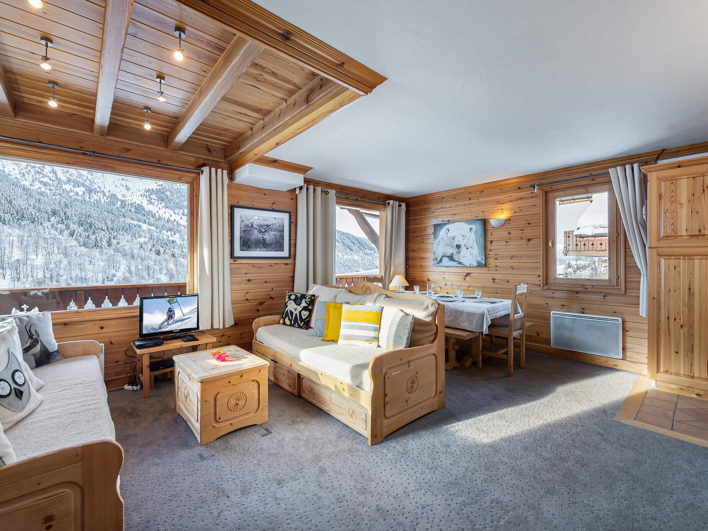 Un chalet confortable avec des murs en bois, un canapé, une table à manger et un téléviseur.