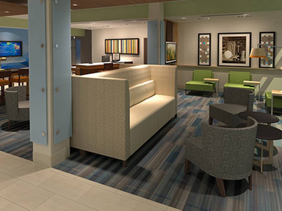 A modern hotel lobby with a sofa, chairs, a TV, and artwork on the walls.