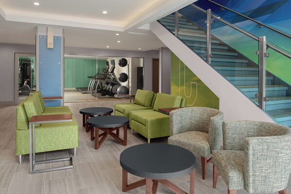 Un espacio interior moderno con zonas de estar, equipo de ejercicio y una escalera.