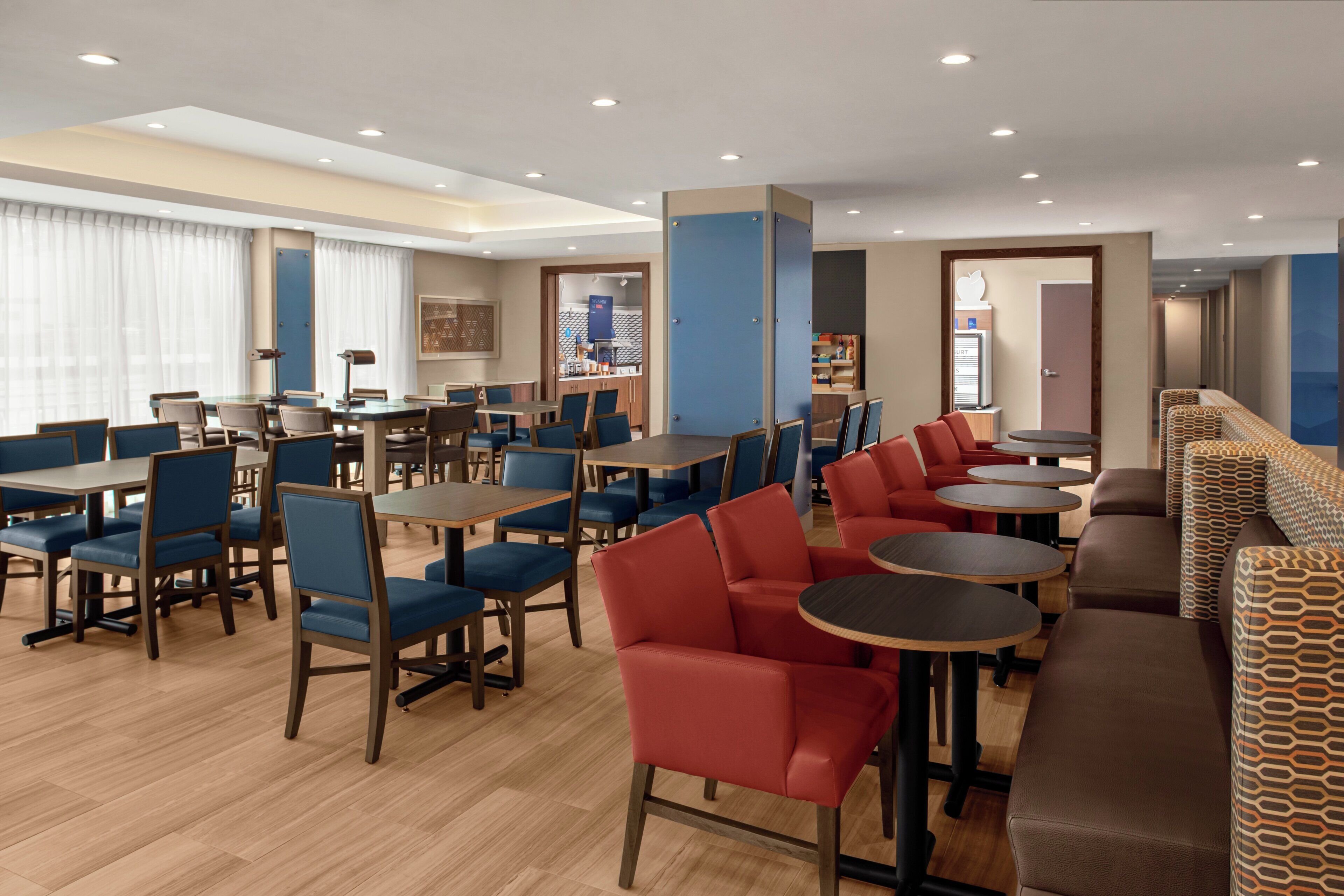 A hotel dining area with multiple tables and chairs, a reception desk, and a counter with a menu.