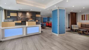 A hotel reception area with a modern design, including a reception desk, seating area, and a dining space. - Holiday Inn Express & Suites Woodside LaGuardia Airport by IHG (Woodside)