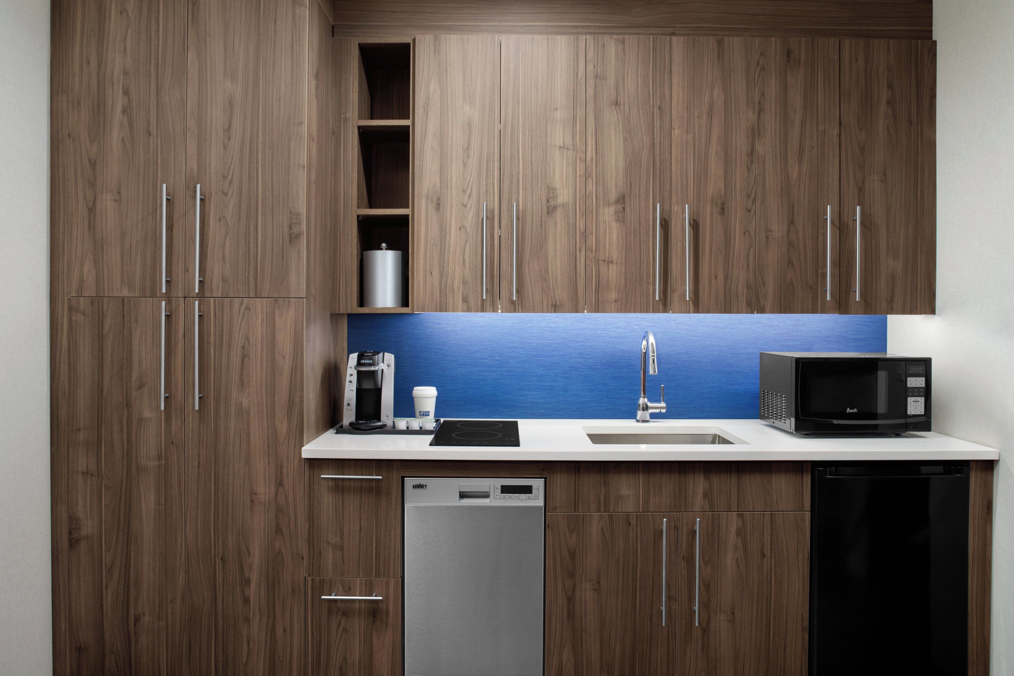A modern kitchen with wooden cabinets, a stainless steel coffee maker, a microwave, and a dishwasher.