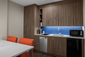Una cocina compacta con armarios de madera, lavavajillas, microondas y fregadero.