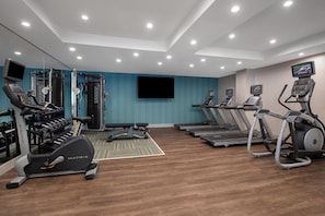 Ein modernes Fitnessstudio mit Laufbändern, Crosstrainern und Gewichtsmaschinen.