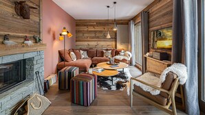 A cozy living room with a fireplace, a sofa set, a coffee table, and a large window with curtains. - New apartment in Méribel with parking, for 6 people (Méribel)