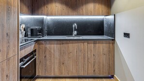 A modern kitchen with wooden cabinetry, a stainless steel sink, and a built-in oven. - New apartment in Méribel with parking, for 6 people (Méribel)