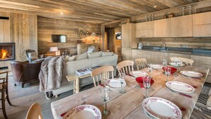 A rustic interior with a dining area, sofa, fireplace, and wooden ceiling. - Ski-In Ski-Out Apartment with Spa Access and Mountain Views in Méribel (Méribel)