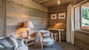 A cozy cabin interior with wooden walls, a dining table, two chairs, a lamp, and a window with curtains. - Ski-In Ski-Out Apartment with Spa Access and Mountain Views in Méribel (Méribel)