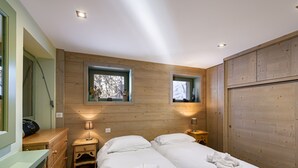 Ein Zimmer mit zwei Betten, Holzwänden, einem Fenster, einem Schminktisch und einem Spiegel.