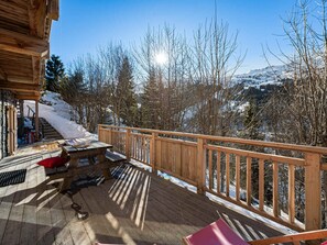 A wooden deck with a wooden railing, a picnic table, and a bench. - Quiet apartment with terrace and parking, close to slopes (Méribel)