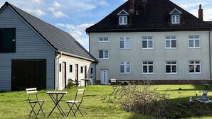 A two-story house with a sloped roof and a small front porch. - Landhaus Karnin - Vacation at the Peenestrom - FEWO3 (Usedom OT Karnin)
