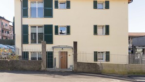 Ein zweigeschossiges Gebäude mit beiger Fassade, grünen Fensterläden und einem eingannten Eingang.