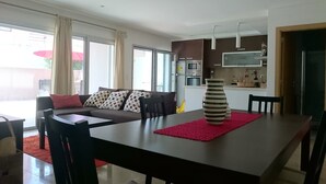 En moderne stue med spisebord, sofa og et køkkenområde.