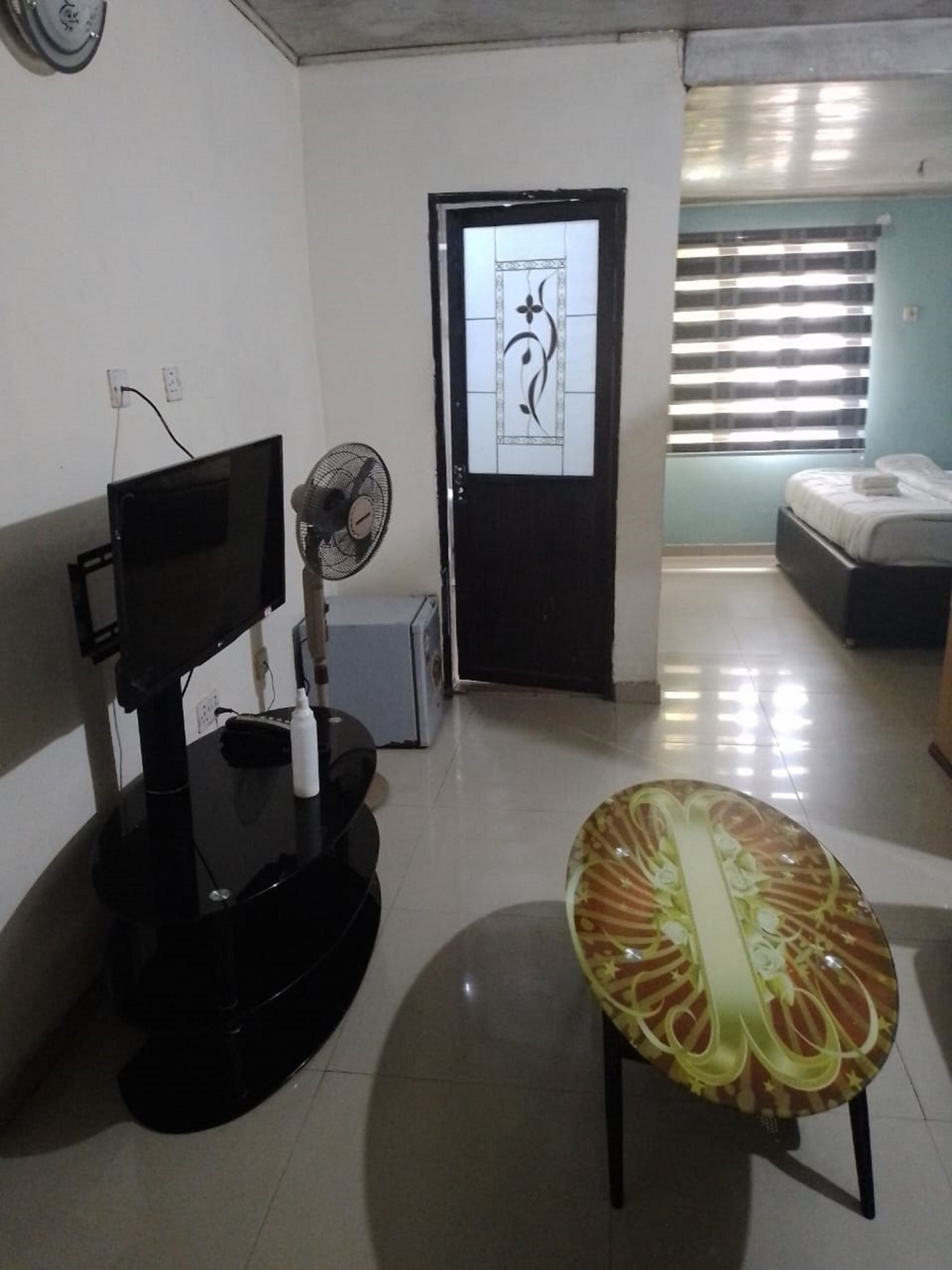 A room with a bed, a TV, a fan, and a decorative table.