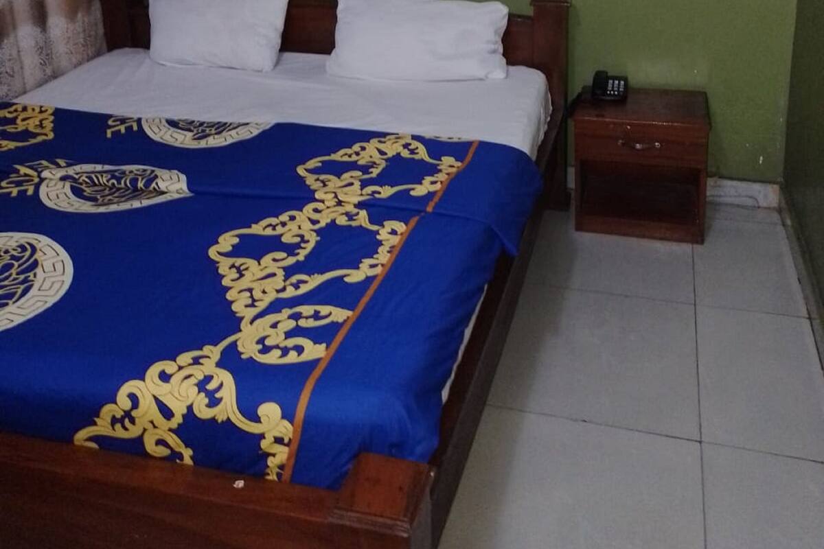 A bedroom with a bed, a nightstand, an air conditioner, and a wall socket.