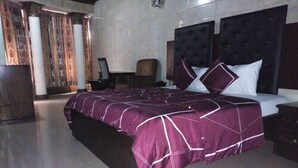 A bedroom with a large bed, a nightstand, a chair, and a desk. - Cynergy Suites Apapa (Lagos)