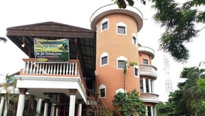 A multi-story building with a curved facade, balconies, and a sign advertising a poolside restaurant. - Cynergy Suites Apapa (Lagos)