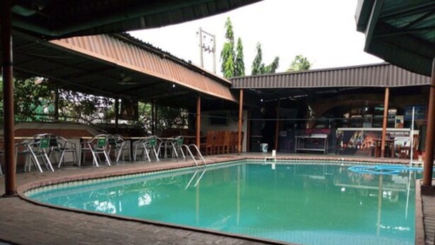 A swimming pool with a covered area, chairs, and a tiled floor. - Cynergy Suites Apapa (Lagos)