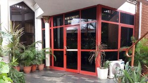 A building entrance with a red door, potted plants, and a tiled floor. - Cynergy Suites Apapa (Lagos)
