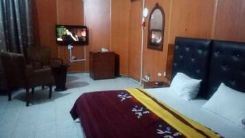 Una habitación de hotel con cama, televisión, silla y una mesita.