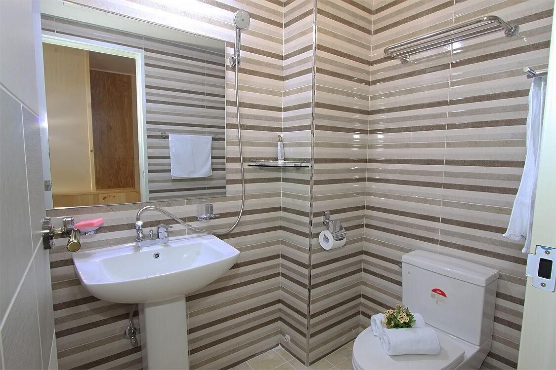 Une salle de bain avec des murs recouverts de carreaux à rayures, un lavabo blanc, une douche et des toilettes.