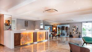 A modern hotel lobby with a reception desk, seating area, and a view of the outside.