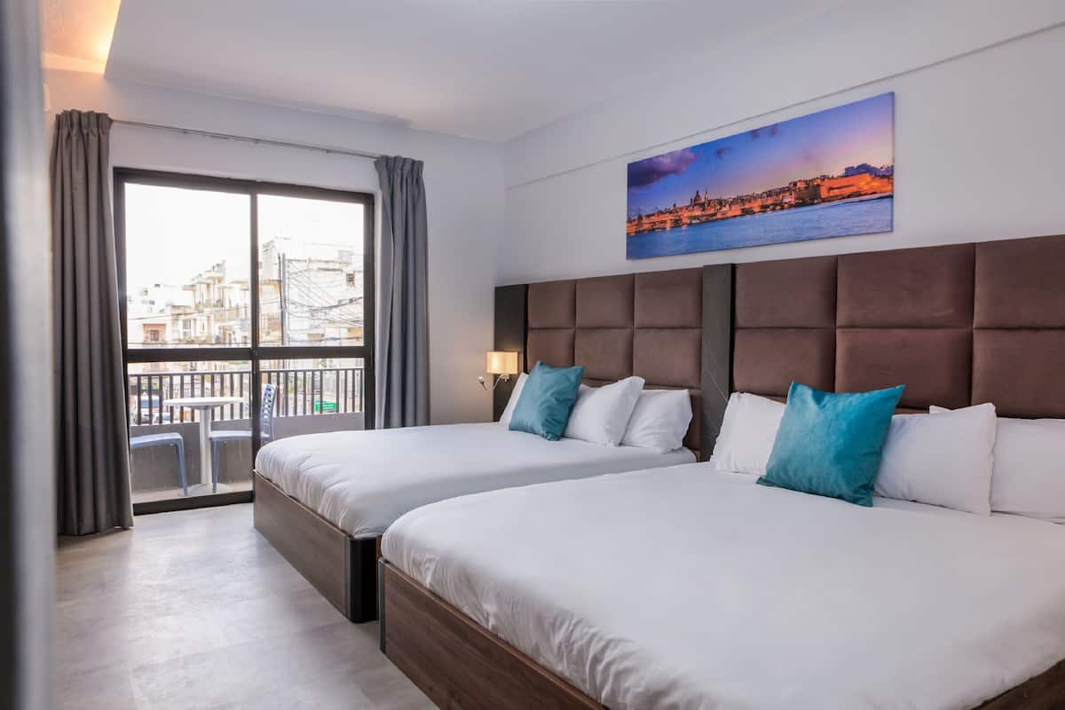 Ein Hotelzimmer mit zwei Betten, einem großen Fenster und Blick auf die Stadt.