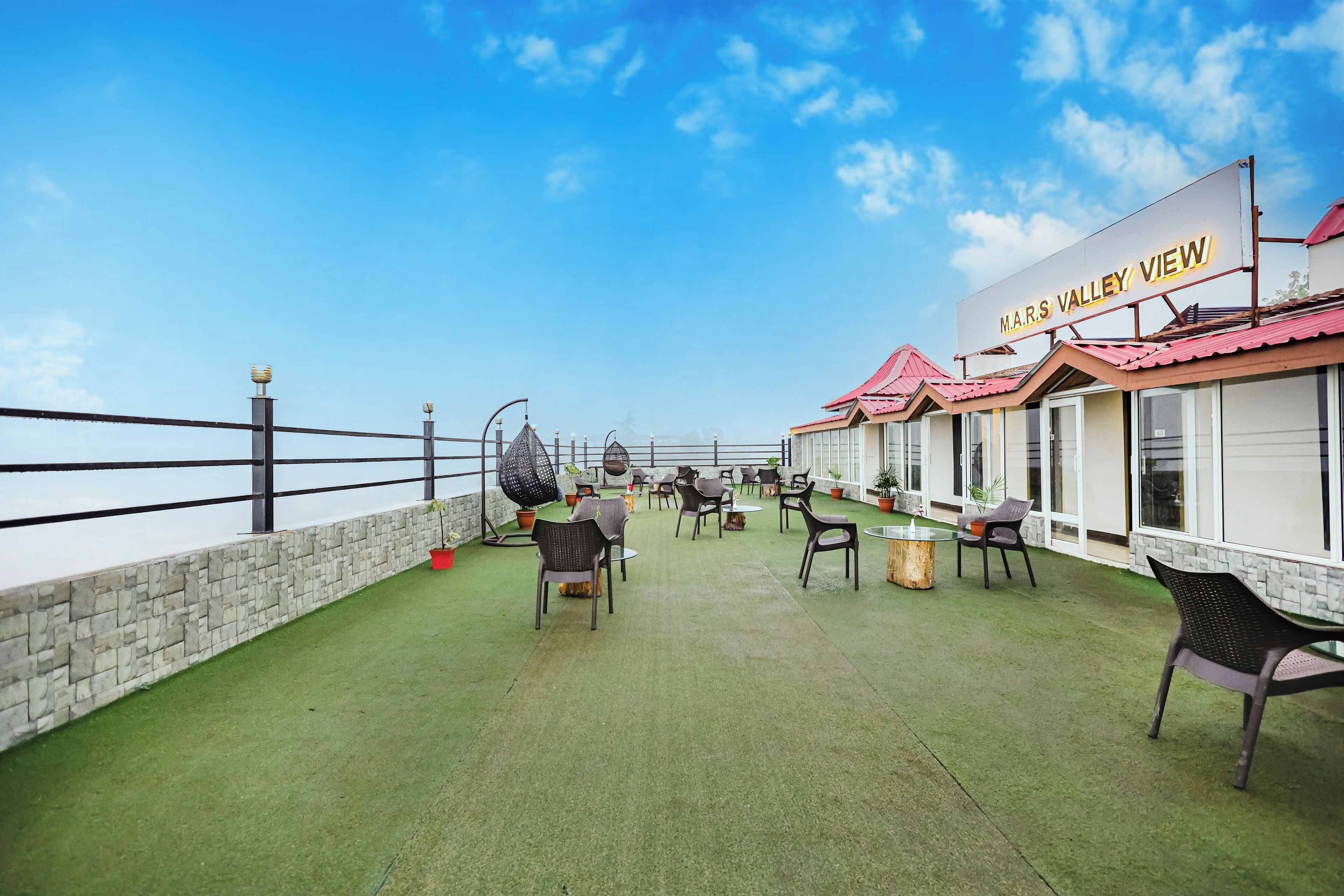 A rooftop terrace with green artificial grass, outdoor seating, and a sign reading "MARS VALLEY VIEW".