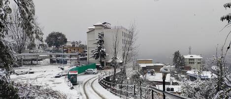 A snowy residential area with buildings, a curved road, and a green sign.