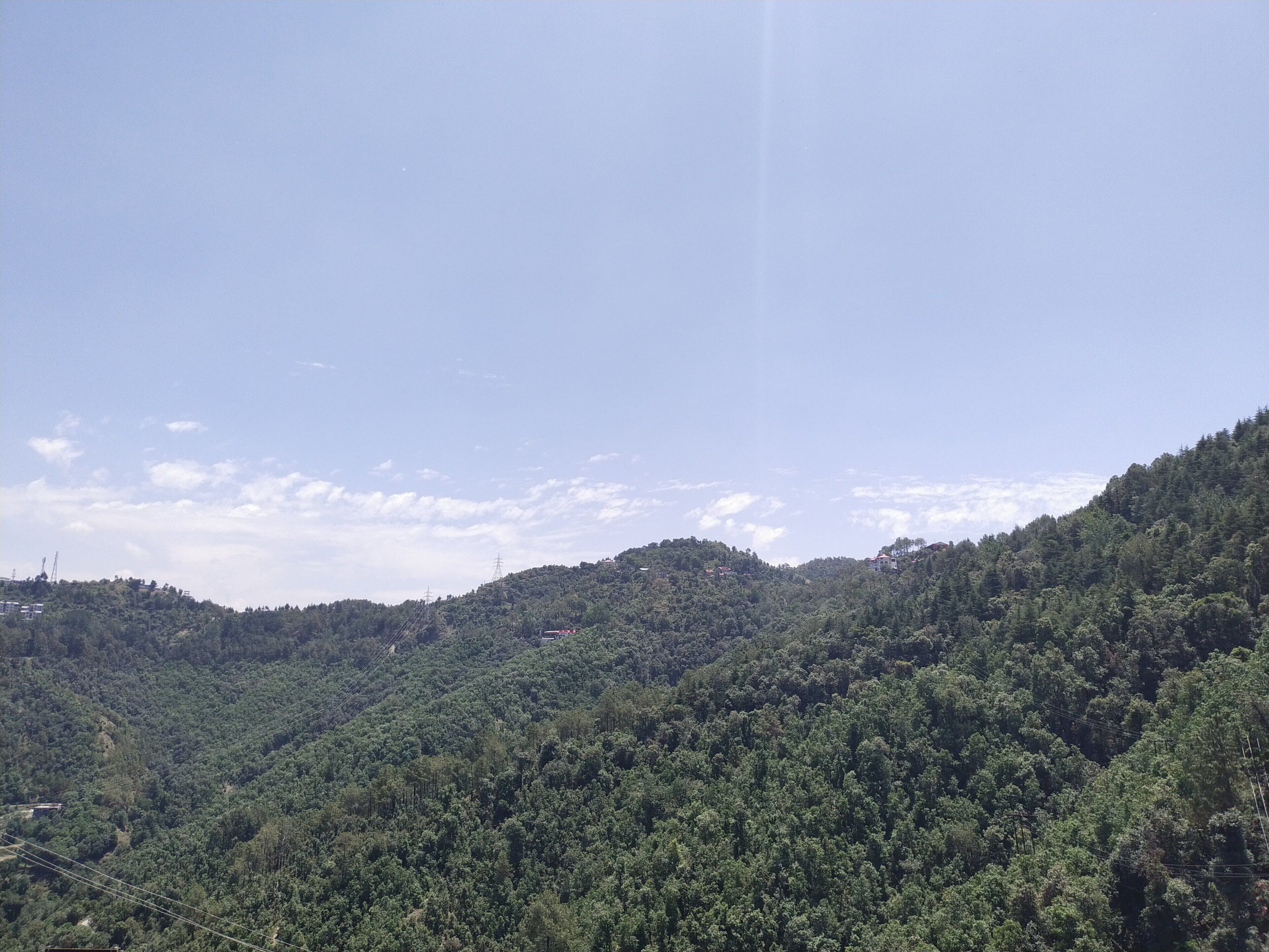 A mountainous landscape with dense forest coverage and a clear sky.