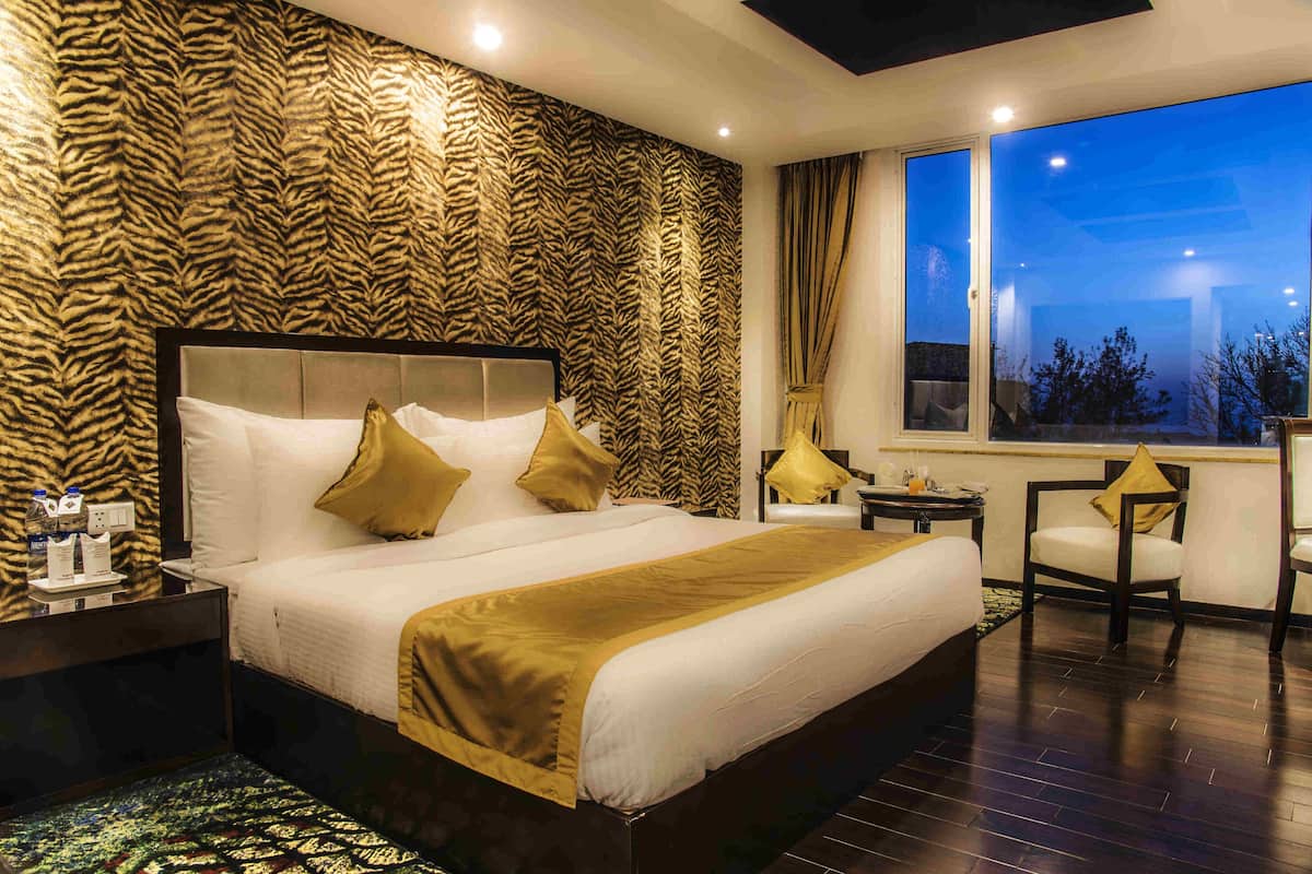 A bedroom with a large bed, a nightstand, a chair, and a window with a view.
