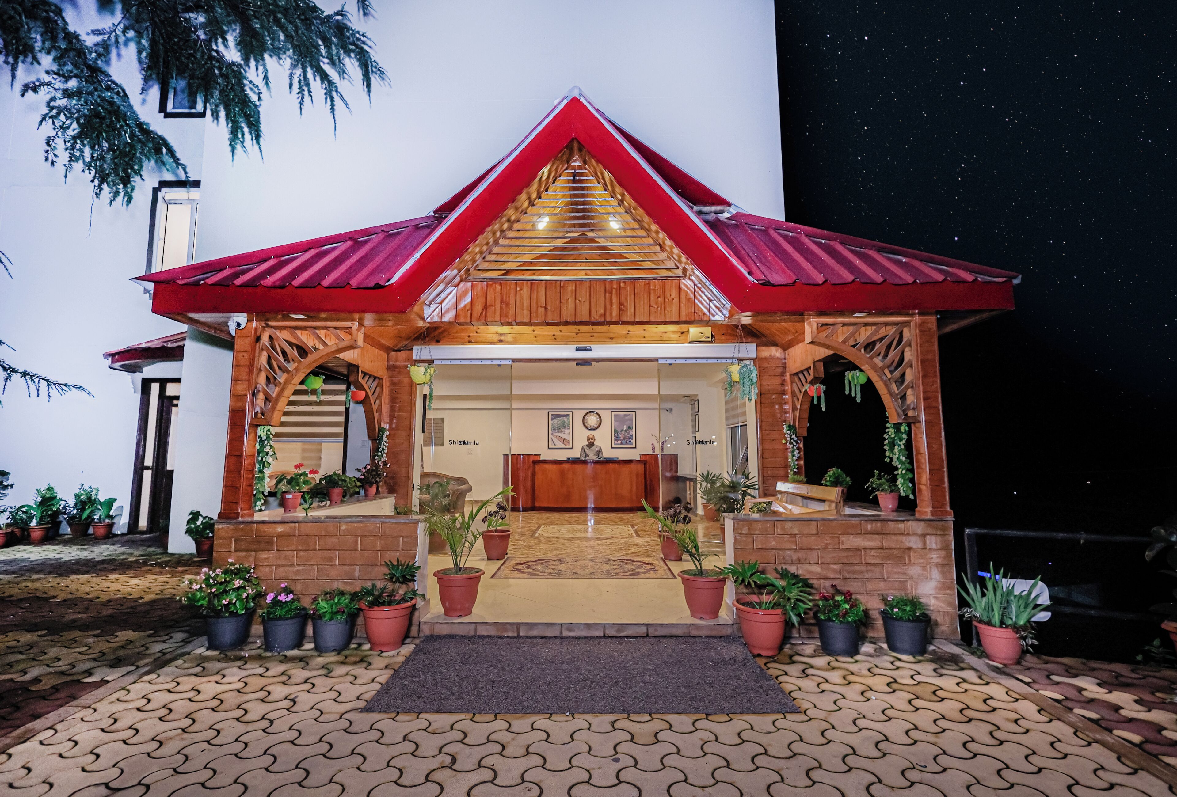 Un kiosque en bois avec un toit rouge, un comptoir d’accueil et des plantes en pot.