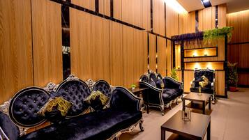 A luxurious lobby with ornate black sofas and wooden paneling.