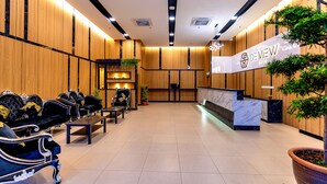 Ein Hotel-Rezeptionsbereich mit einem Marmor-Empfangstresen, komfortablen Sitzmöglichkeiten und Holzvertäfelung.