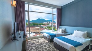 Ein Hotelzimmer mit zwei Betten, einem Fernseher und einem großen Fenster mit Blick auf die Stadt.