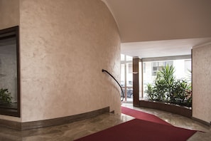 Enter a stylish lobby with a curved wall design, red carpet, and a large window offering a view of the outside.