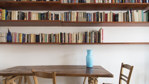 Ein Holztisch mit Stühlen und einem Bücherregal voller Bücher.