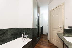 A modern bathroom with a marble vanity, a glass shower enclosure, and a white door.