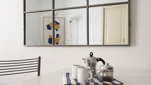 Un comedor con una mesa blanca, una silla negra y un espejo grande que refleja la habitación.