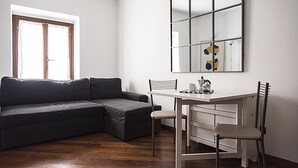 Una sala de estar moderna con un sofá modular, una mesa de comedor con dos sillas y un espejo grande en la pared.