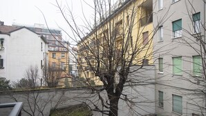A multi-story building with balconies, a tree in the foreground, and a clear view of the street. - Studio Flat in a Quiet Place (Milan)